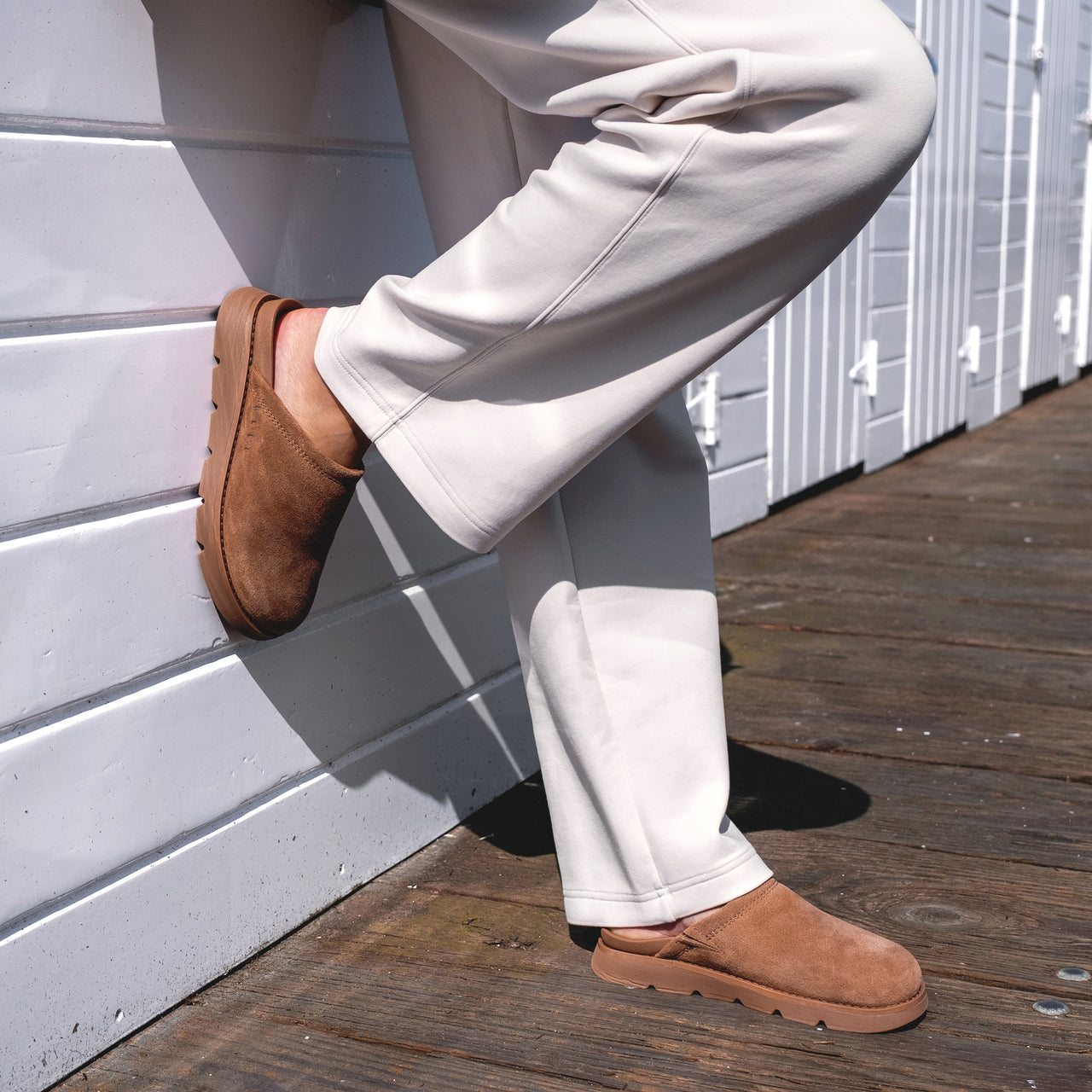 Vista Luxe Mariana shown facing right, brown suede clog worn with beige pants on wooden deck, emphasizing comfort and style.
