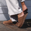 Close-up of left foot wearing brown suede Vista Luxe Mariana clog facing right, showing slip-on design and textured sole.