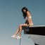 Woman wearing Reef Water Vista sandals facing left, sitting on boat edge, showcasing soft-rebound cushioning and arch support.