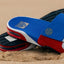 Pair of Fanning Slide sandals facing left in red, white, and blue with cushioned EVA footbeds on sand background