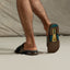 Fanning + Slide facing away, men's brown and spruce water-friendly slides with oversized airbag heel and REEFlex cushioning.