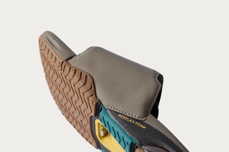 Close-up of the slide sandal’s sole and upper facing left, showing textured outsole and cushioned footbed with Reelflex Foam.