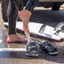 man coming back from surfing washing off his feet with black sandals